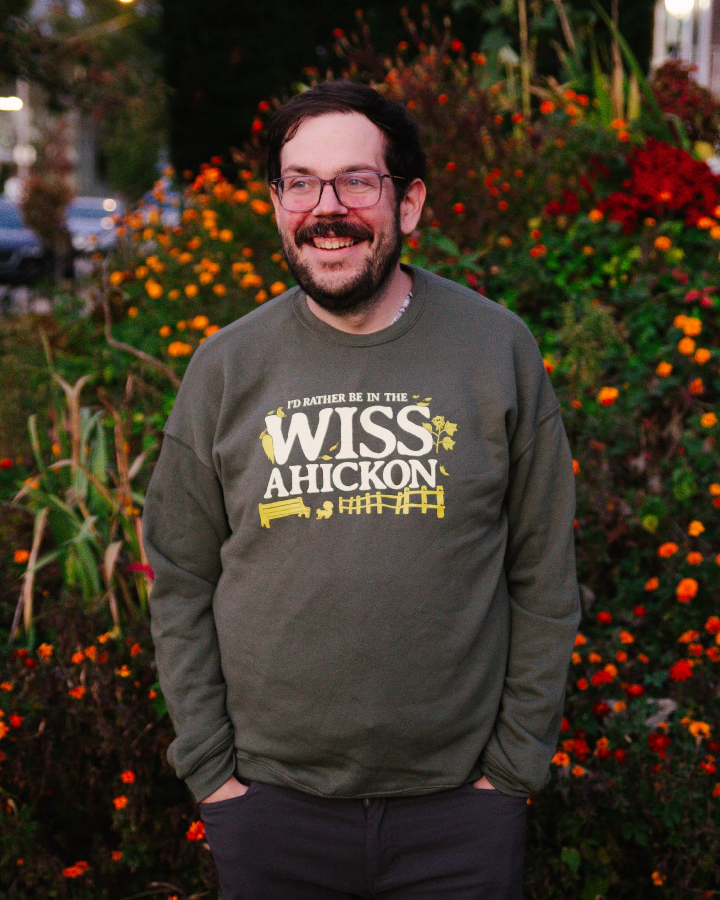 Man wearing a sweatshirt with 'WISS AHICKON' text standing in front of flowers