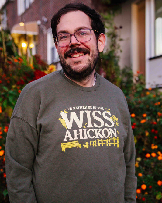 Man wearing a sweatshirt with 'WISSAHICKON' text and graphics outdoors.