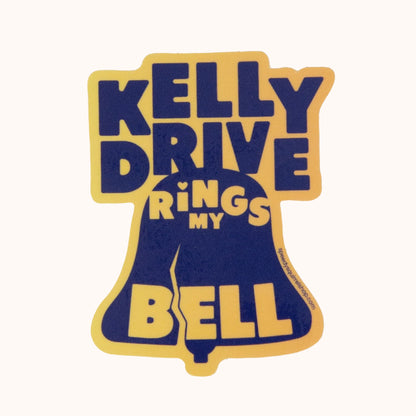 A blue and yellow waterproof vinyl sticker with the text 'KELLY DRIVE RINGS MY BELL' designed in the shape of a bell.