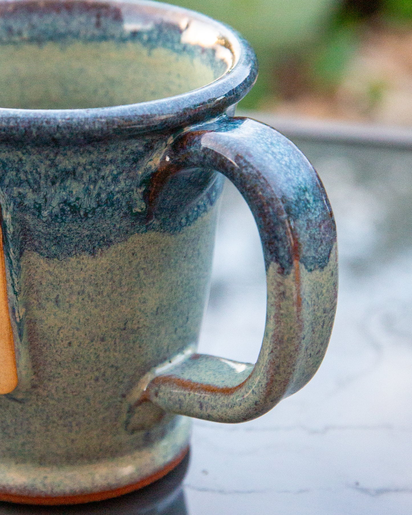 Blue ceramic mug with a handle on a glass surface