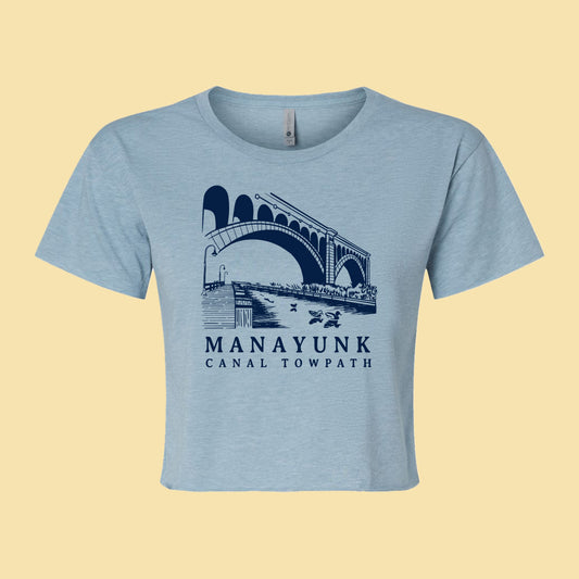 light blue crop topt with a bridge and nature graphic and 'Manayunk Canal Tow Path' text.