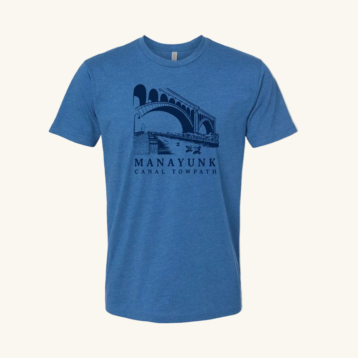 Cool blue t-shirt with a navy blue graphic of a trail and bridge and text 'Manayunk Canal Towpath' on a tan background.