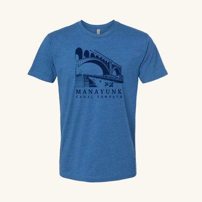 Cool blue t-shirt with a navy blue graphic of a trail and bridge and text 'Manayunk Canal Towpath' on a tan background.