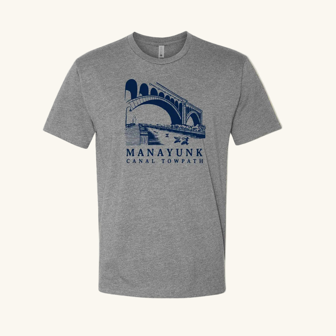 Heather gray t-shirt with a navy blue graphic of a trail and bridge and text 'Manayunk Canal Towpath' on a tan background.