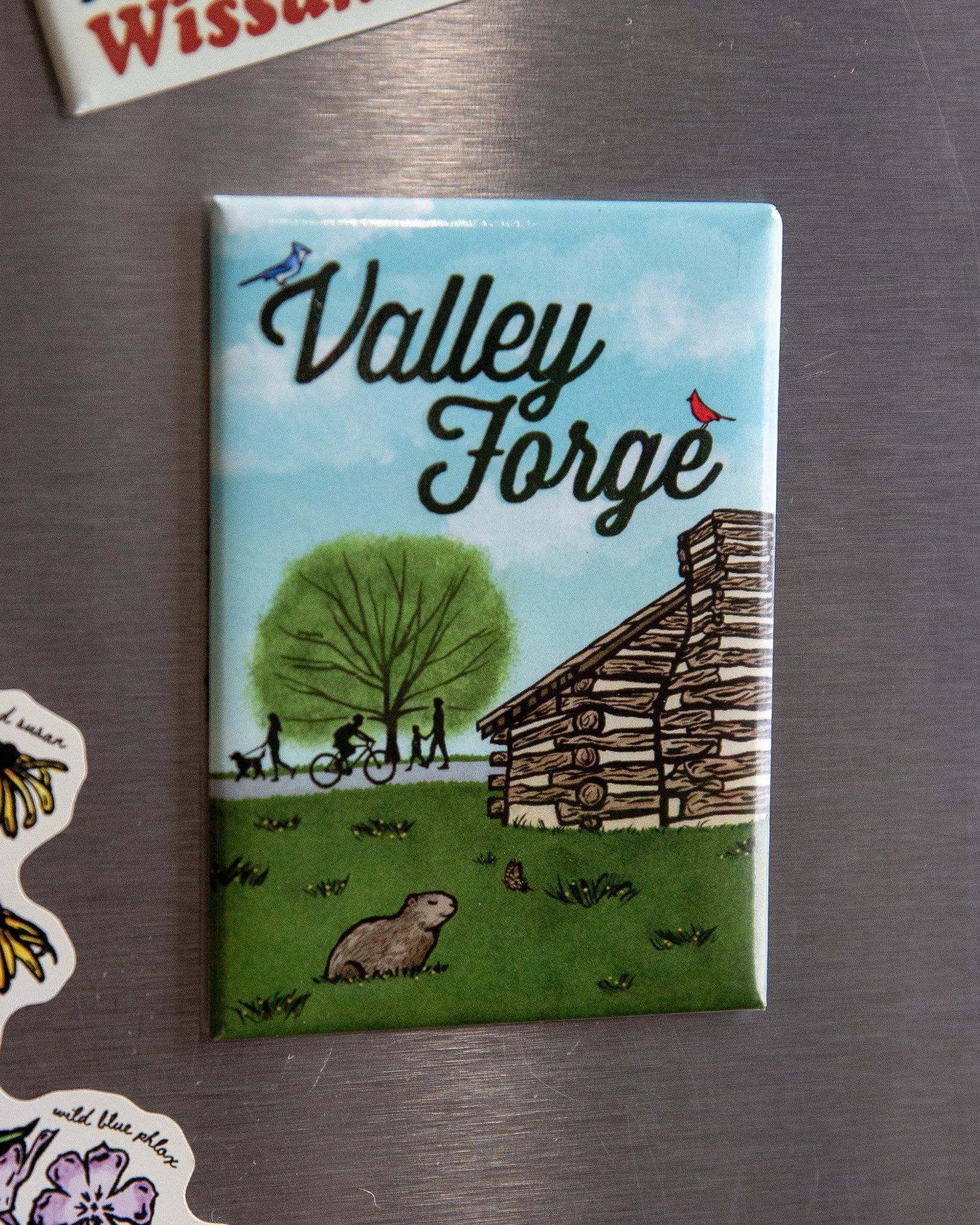 Fridge magnet with 'Valley Forge' design featuring a cabin and nature on a metallic surface.