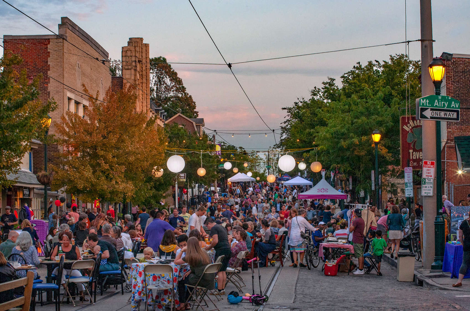 Street scene with people gathered for an outdoor event at dusk.