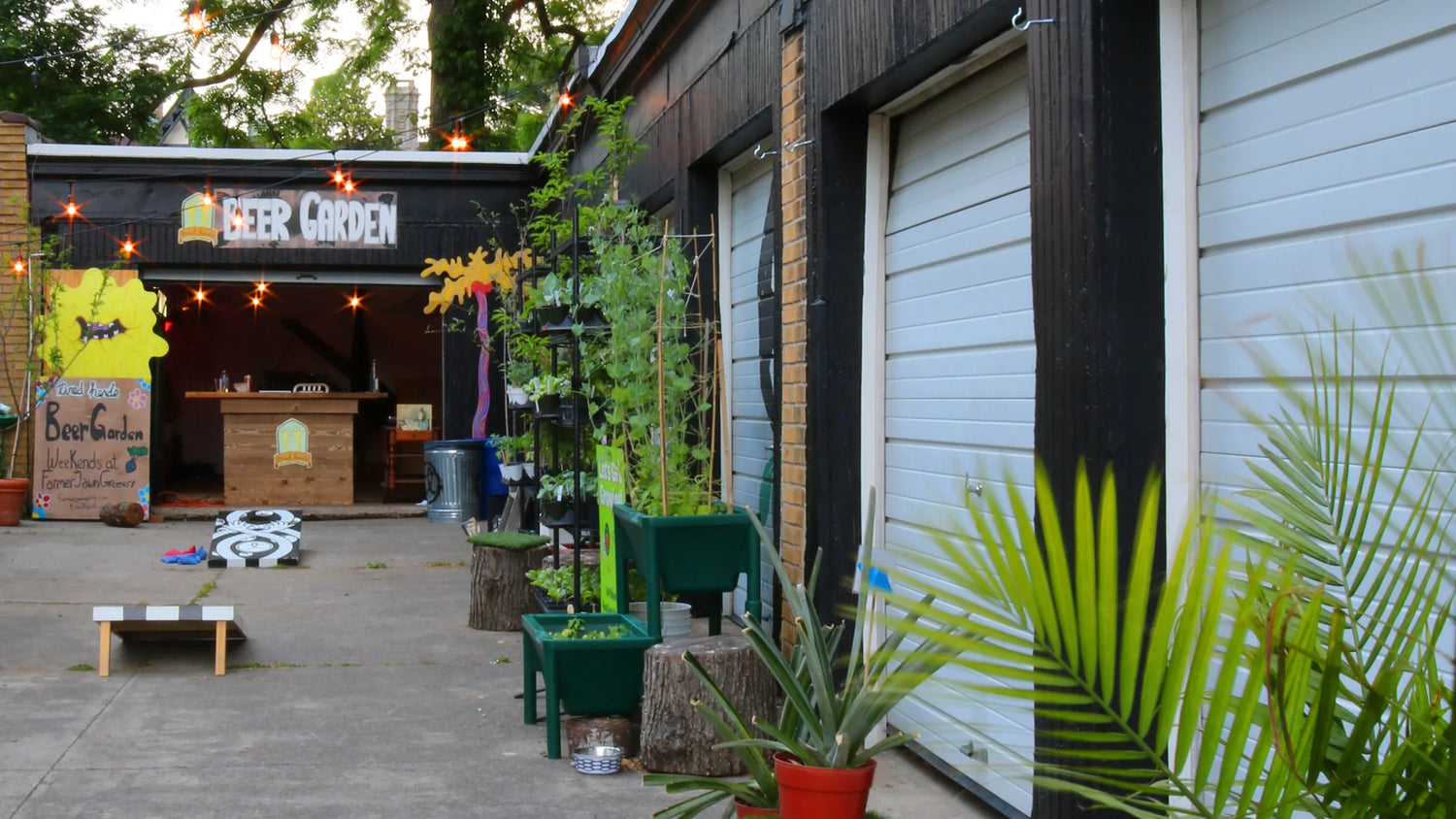 Outdoor patio area with plants and a bar sign on a building.