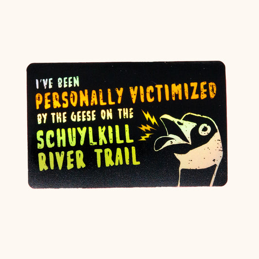 Holographic sticker with text saying "I've been personally victimized by the geese on the Schuylkill River Trail" with a goose hissing