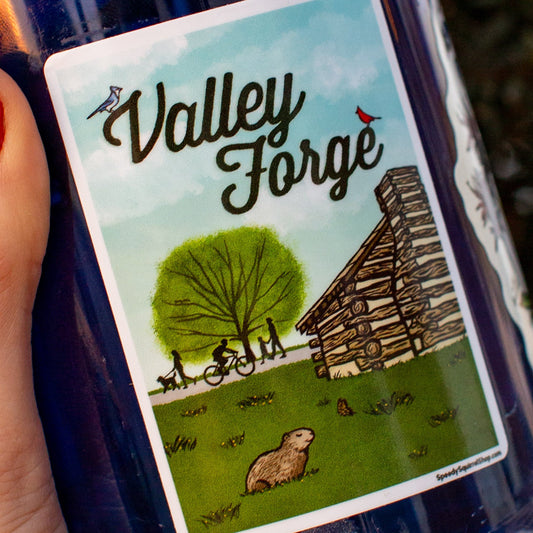Blue water bottle with a Valley Forge sticker Illustration of a log cabin, tree, and people on a bike and footpath. 