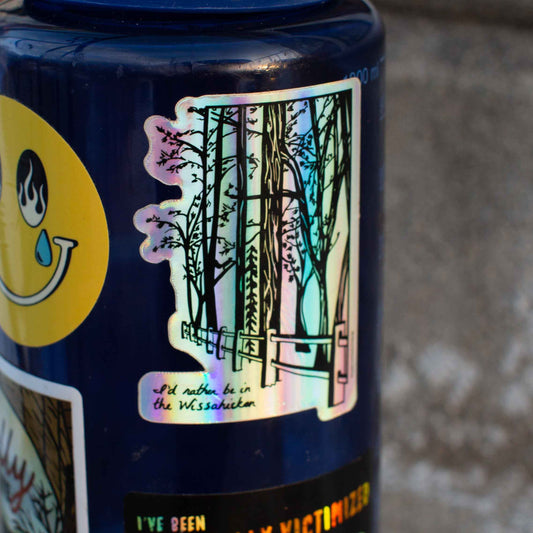 A holographic sticker with an illustration of the Wissahickon Valley Park, featuring trees and a pathway, on a blue water bottle