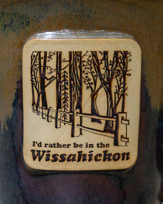 Mugwith a forest design and text 'I'd rather be in the Wissahickon' on a textured background.