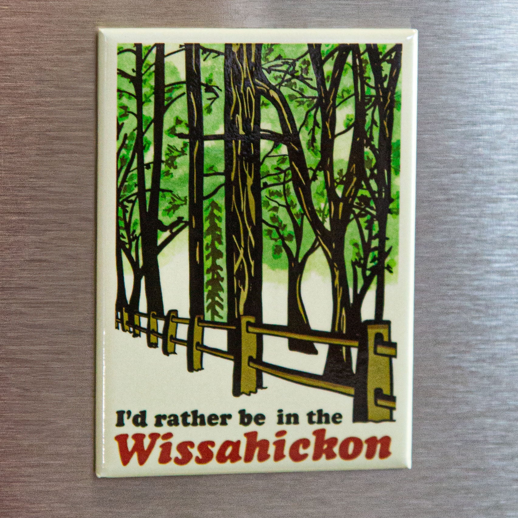 Fridge magnet with a forest design and text 'I'd rather be in the Wissahickon' on a metallic surface.